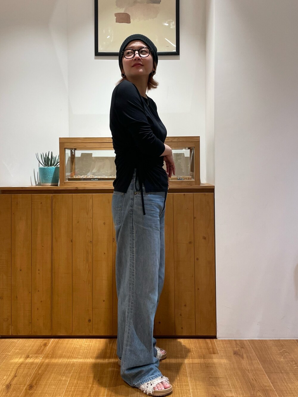 ブラック系のTシャツ/カットソー、ブルー系のデニムパンツ、ホワイト系のサンダルを着用したレディースの春コーディネートの3枚目の写真