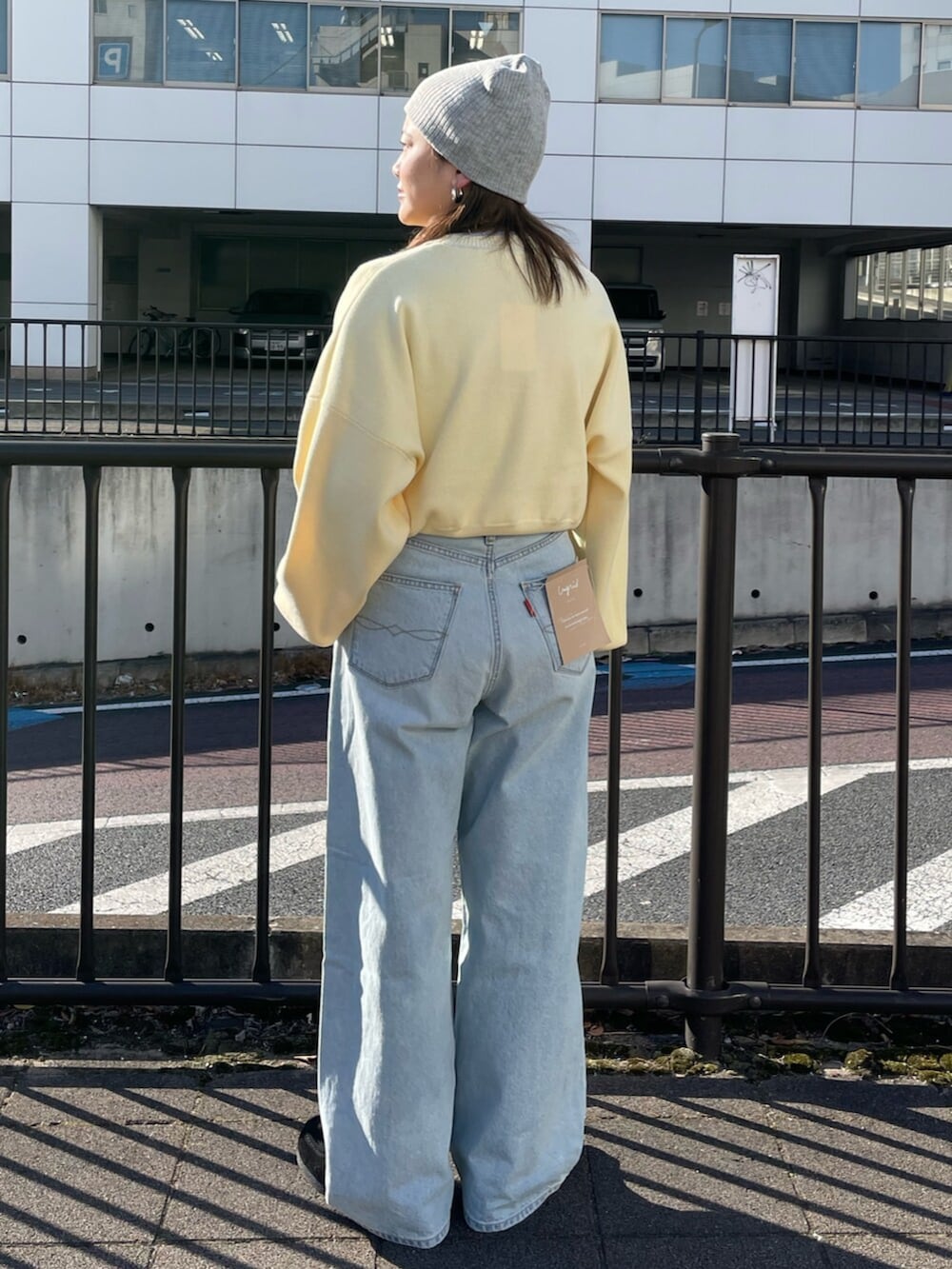 イエロー系のニット/セーター、ブルー系のデニムパンツ、グレー系のニットキャップ/ビーニーを着用したレディースの冬コーディネートの3枚目の写真