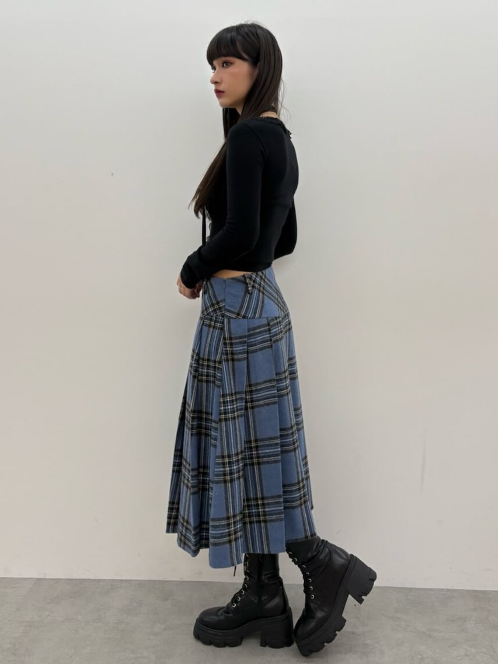 ブラック系のブーツ、ブラック系のニット/セーター、ブルー系のスカートを着用したレディースの秋コーディネートの3枚目の写真