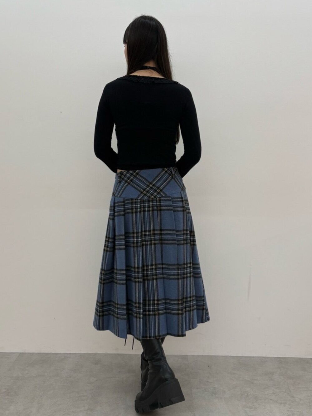 ブラック系のブーツ、ブラック系のニット/セーター、ブルー系のスカートを着用したレディースの秋コーディネートの4枚目の写真