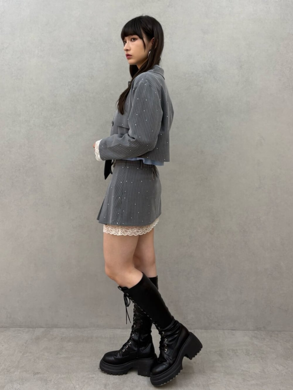 ブラック系のブーツ、グレー系のテーラードジャケット、グレー系のスカートを着用したレディースの冬コーディネートの3枚目の写真