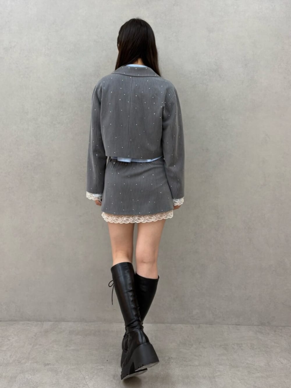 ブラック系のブーツ、グレー系のテーラードジャケット、グレー系のスカートを着用したレディースの冬コーディネートの4枚目の写真