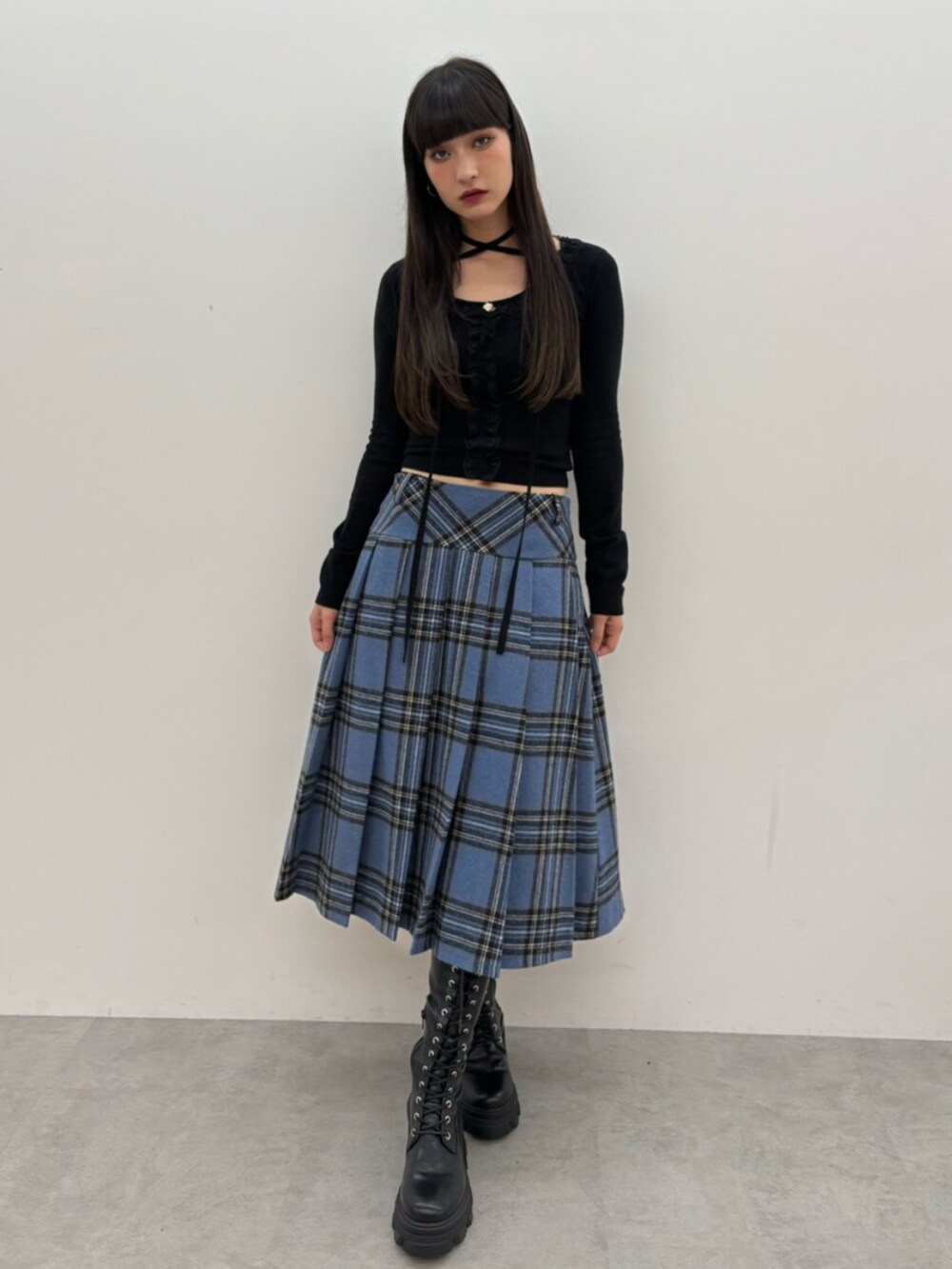 ブラック系のブーツ、ブラック系のニット/セーター、ブルー系のスカートを着用したレディースの秋コーディネートの2枚目の写真