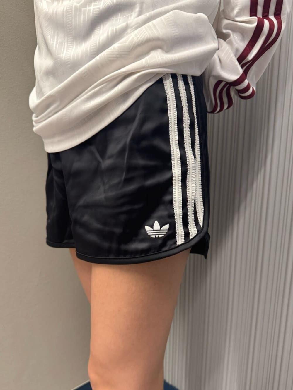 ホワイト系のポロシャツ、ブラック系のその他パンツ、ベージュ系のスニーカーを着用したレディースの夏コーディネートの3枚目の写真