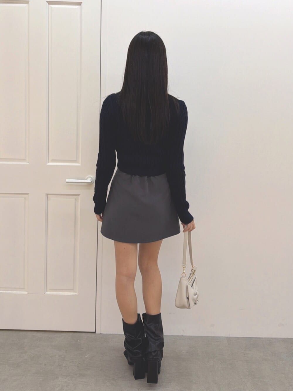 ブルー系のニット/セーター、グレー系のスカート、ブラック系のブーツを着用したレディースの冬コーディネートの3枚目の写真