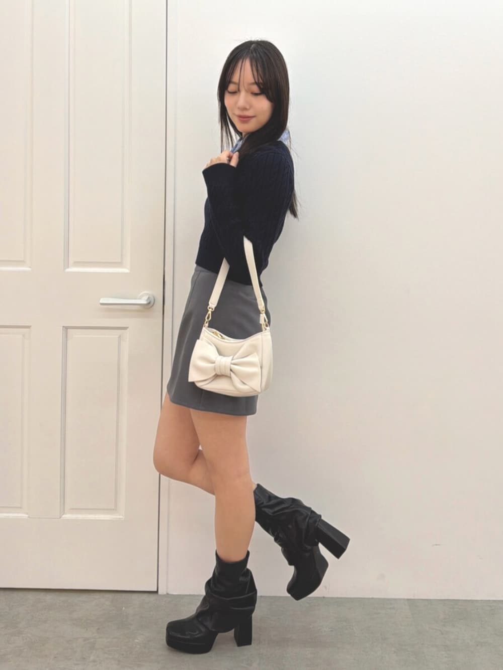 ブルー系のニット/セーター、グレー系のスカート、ブラック系のブーツを着用したレディースの冬コーディネートの2枚目の写真