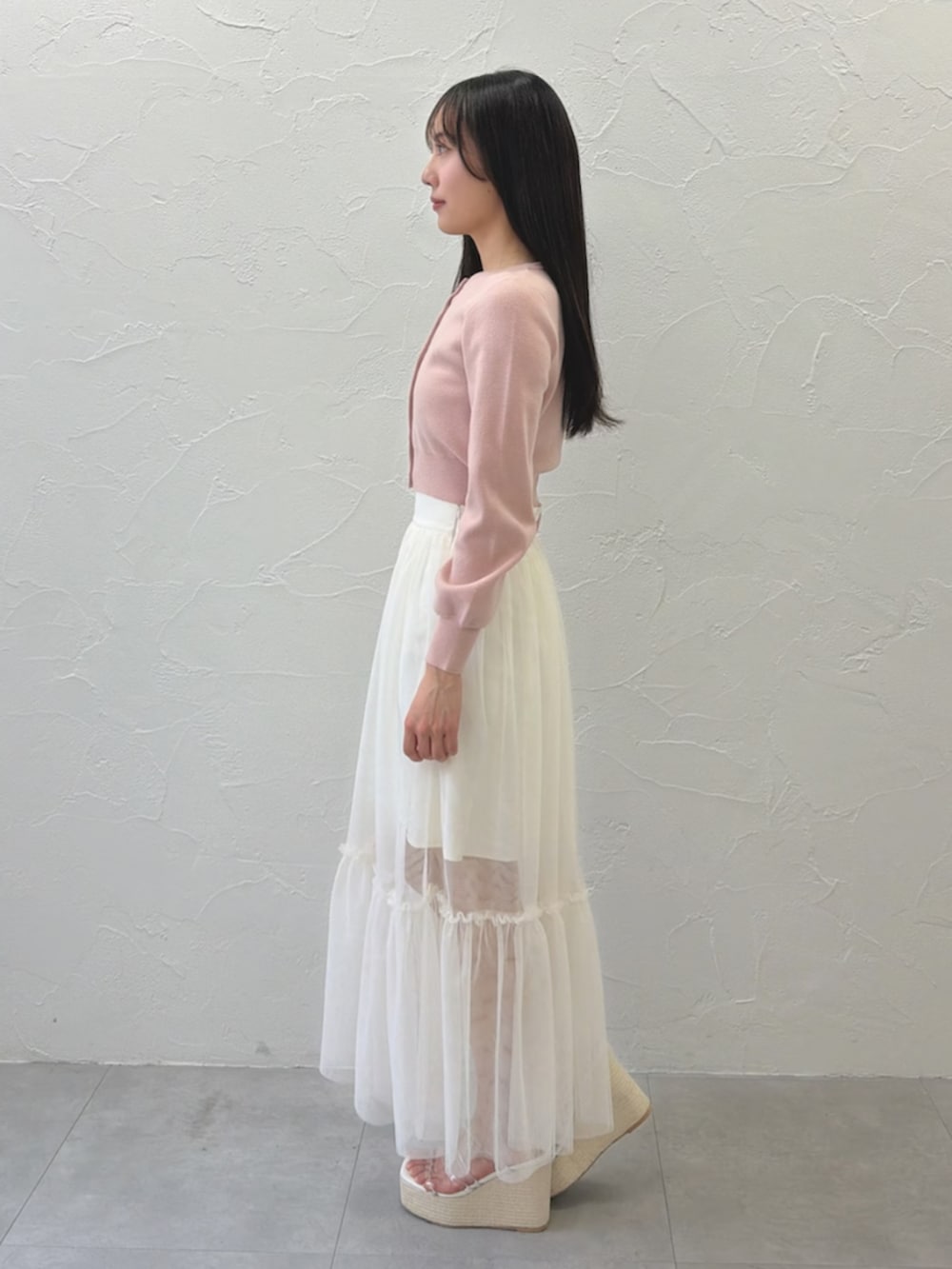 ホワイト系のスカート、ピンク系のカーディガン/ボレロ、ホワイト系のサンダルを着用したレディースの春コーディネートの2枚目の写真
