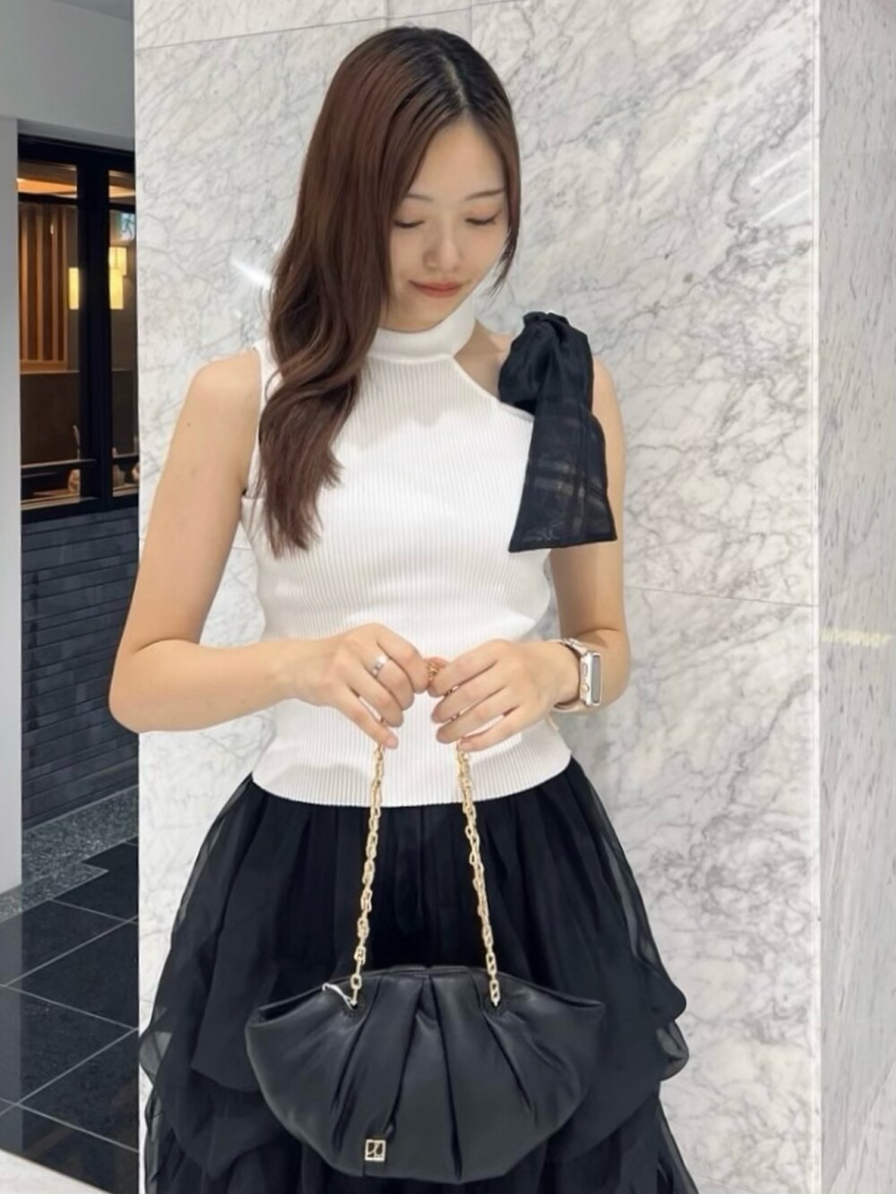 ブラック系のパンプス、ホワイト系のニット/セーター、ブラック系のスカートを着用したレディースの夏コーディネートの3枚目の写真