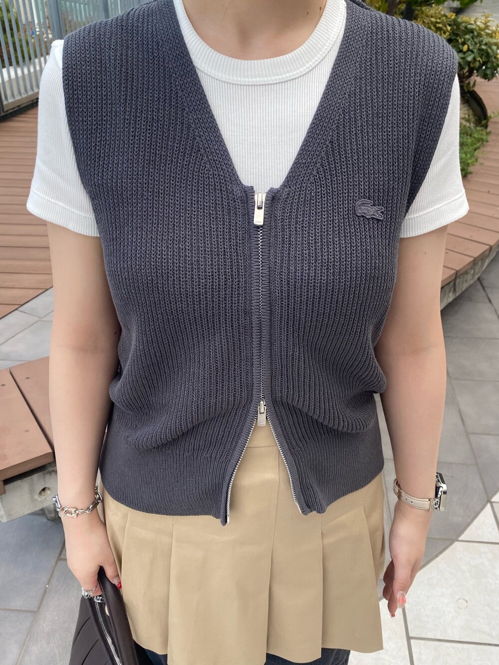 グレー系のベスト、ホワイト系のTシャツ/カットソー、ベージュ系のスカートを着用したレディースの秋コーディネートの4枚目の写真