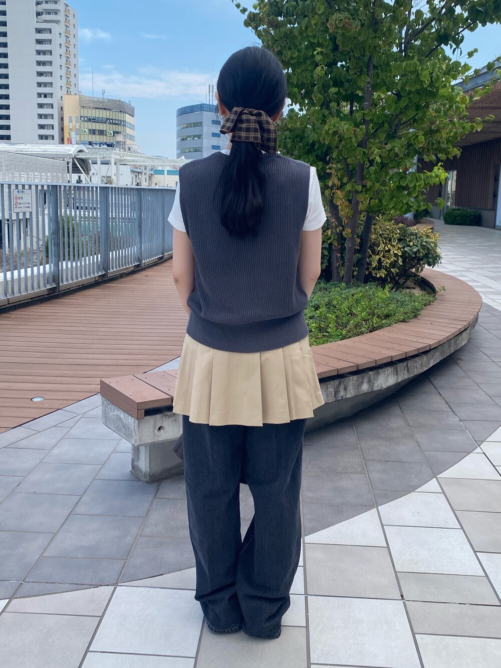 グレー系のベスト、ホワイト系のTシャツ/カットソー、ベージュ系のスカートを着用したレディースの秋コーディネートの3枚目の写真