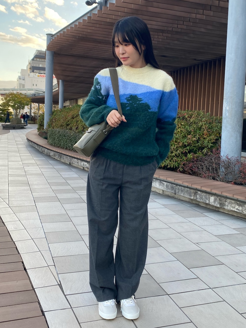 グリーン系のニット/セーター、グレー系のその他パンツ、ホワイト系のスニーカーを着用したレディースの冬コーディネートの2枚目の写真