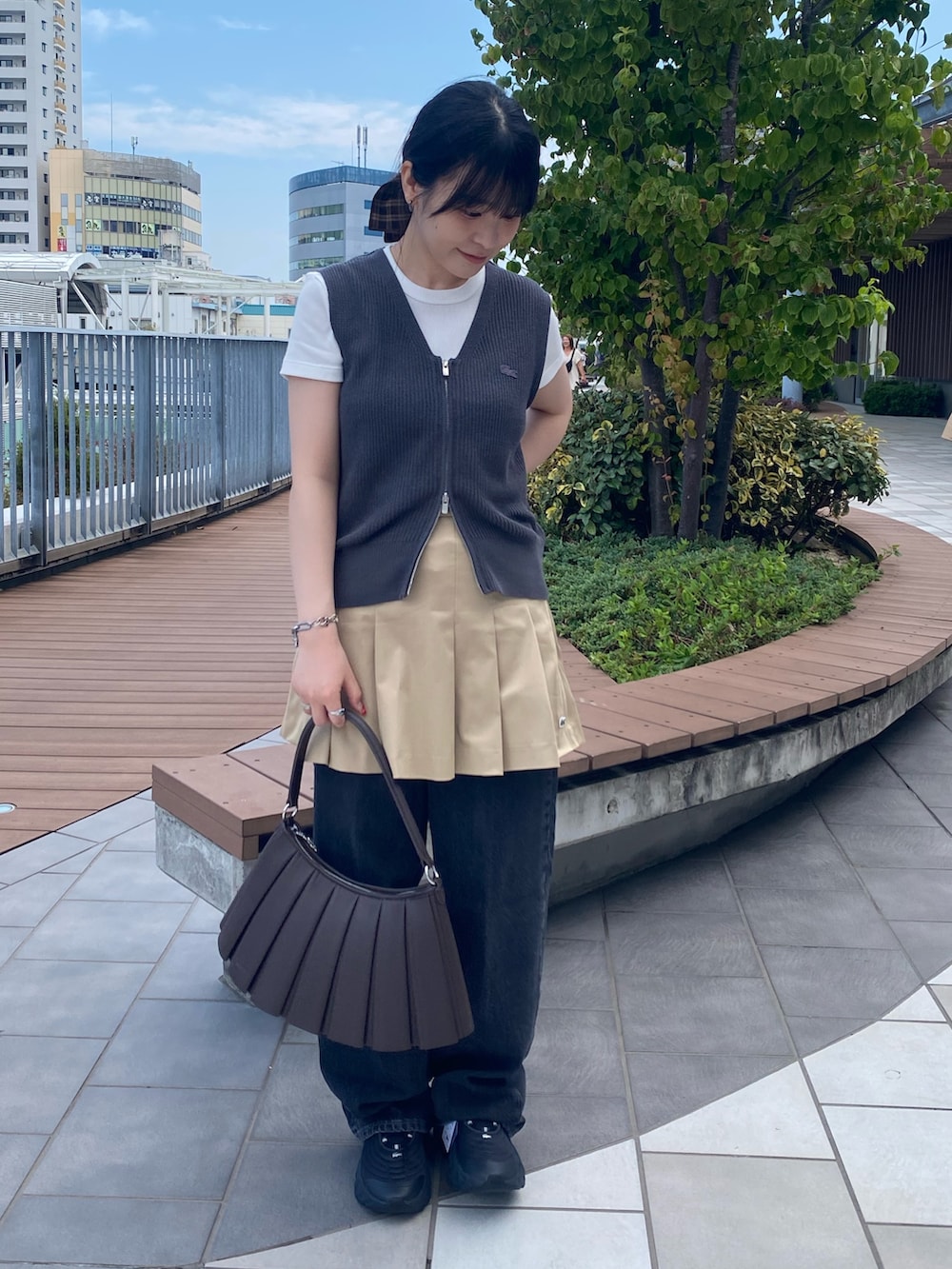 グレー系のベスト、ホワイト系のTシャツ/カットソー、ベージュ系のスカートを着用したレディースの秋コーディネートの2枚目の写真