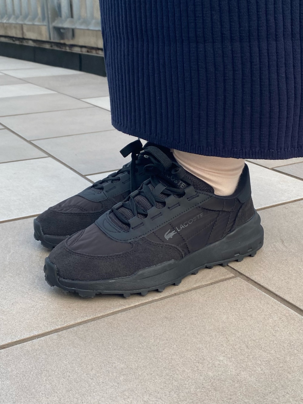 グレー系のピーコート、ブルー系のワンピース、ブラック系のバッグを着用したレディースの冬コーディネートの6枚目の写真