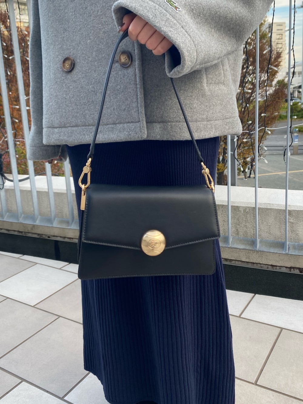 グレー系のピーコート、ブルー系のワンピース、ブラック系のバッグを着用したレディースの冬コーディネートの5枚目の写真