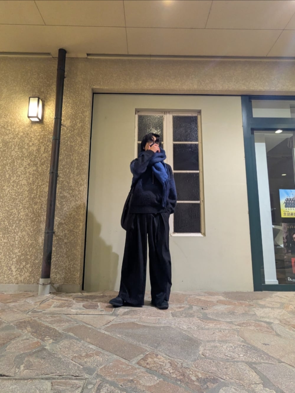 ブラック系のニット/セーター、ブラック系のスラックス、ブルー系のマフラーを着用したメンズの秋コーディネートの2枚目の写真