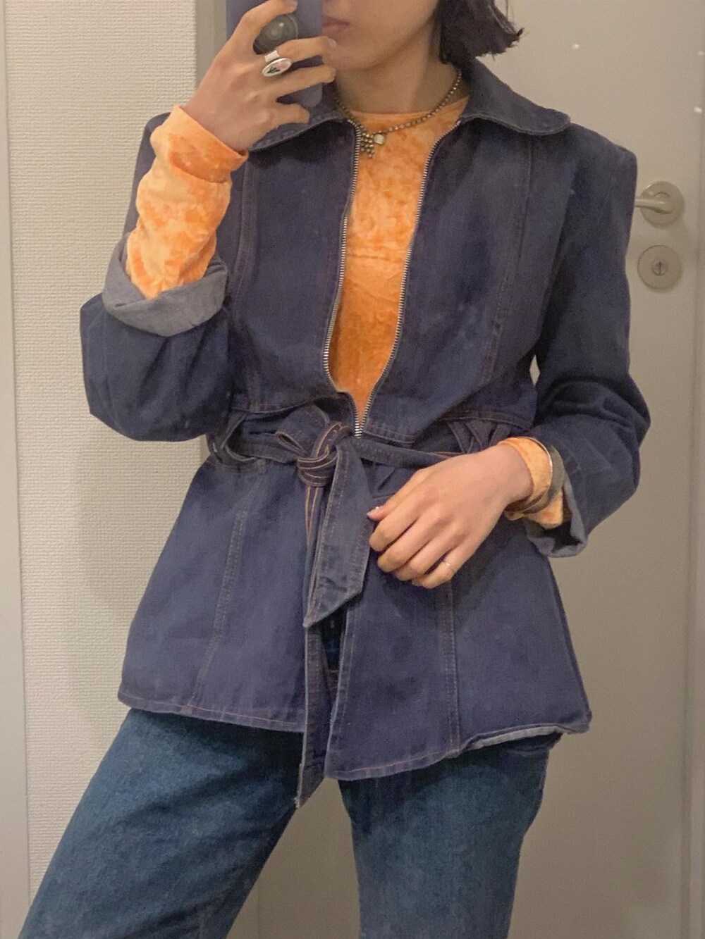 オレンジ系のTシャツ/カットソー、ベージュ系のショルダーバッグ、ブルー系のデニムパンツを着用したレディースの春コーディネートの3枚目の写真