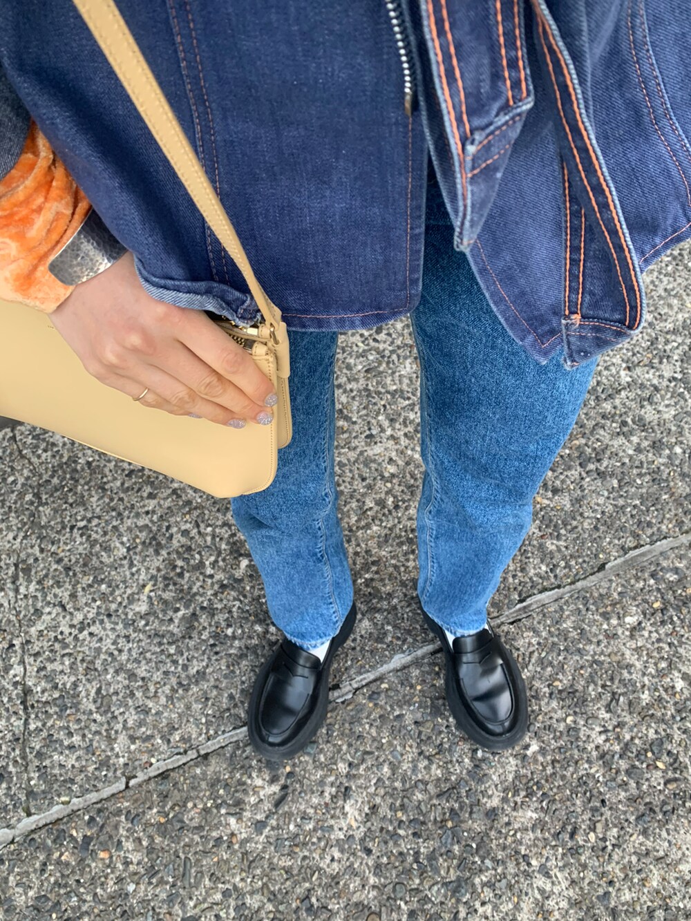 オレンジ系のTシャツ/カットソー、ベージュ系のショルダーバッグ、ブルー系のデニムパンツを着用したレディースの春コーディネートの4枚目の写真