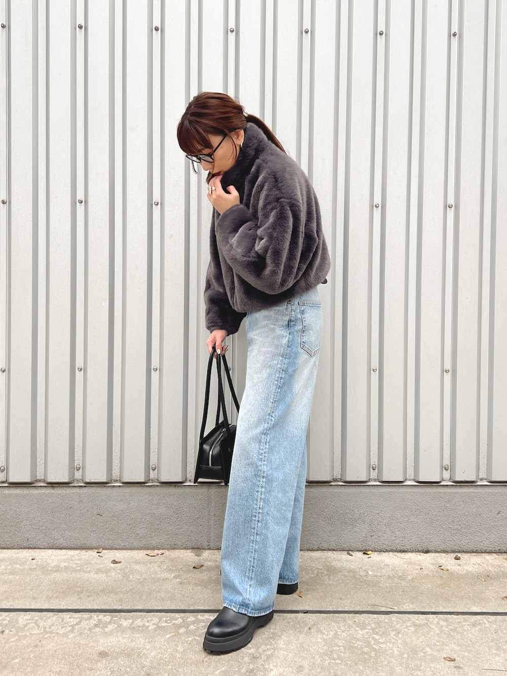 グレー系のブルゾン、ブルー系のデニムパンツ、ブラック系のブーツを着用したレディースの秋コーディネートの5枚目の写真