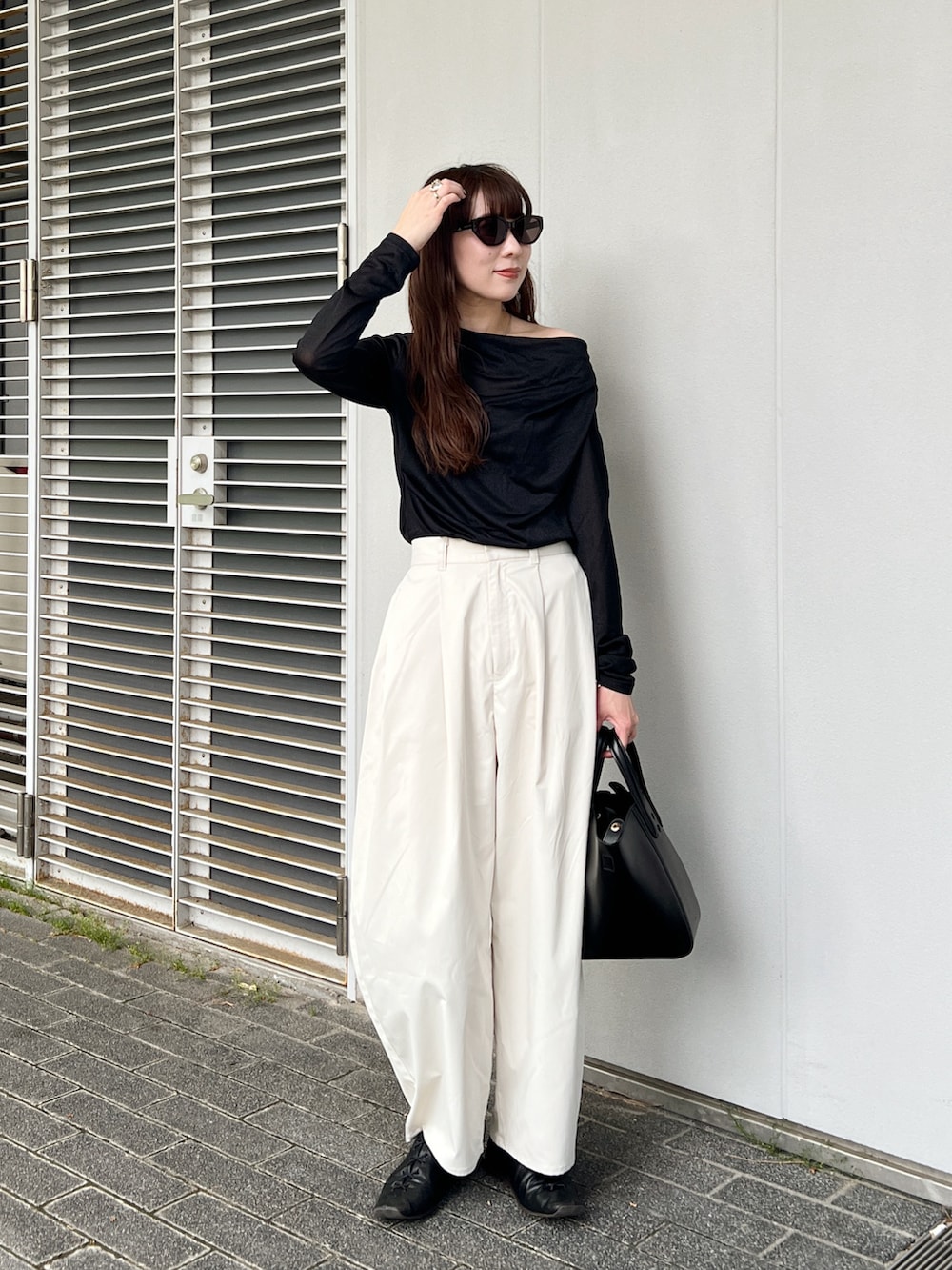 ブラック系のTシャツ/カットソー、ホワイト系のその他パンツ、ブラック系のバッグを着用したレディースの春コーディネートの2枚目の写真
