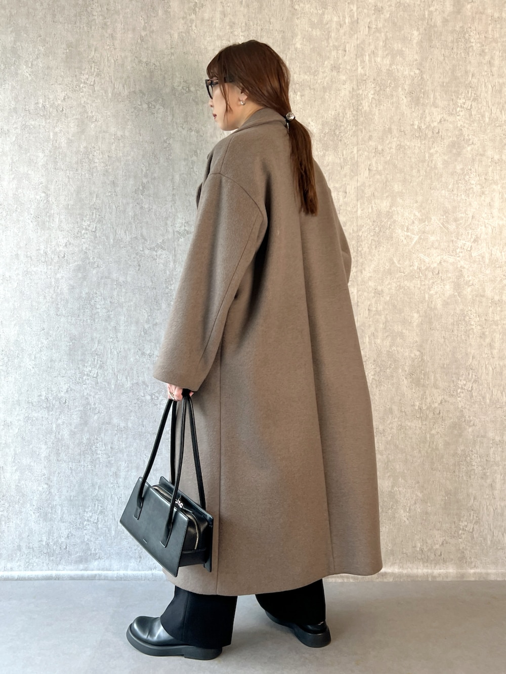 ブラウン系のチェスターコート、ブラック系のその他パンツ、ホワイト系のTシャツ/カットソーを着用したレディースの冬コーディネートの3枚目の写真