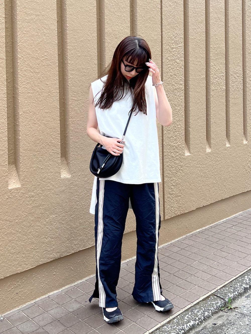 ブラック系のスニーカー、ブラック系のその他パンツ、ホワイト系のTシャツ/カットソーを着用したレディースの夏コーディネートの2枚目の写真