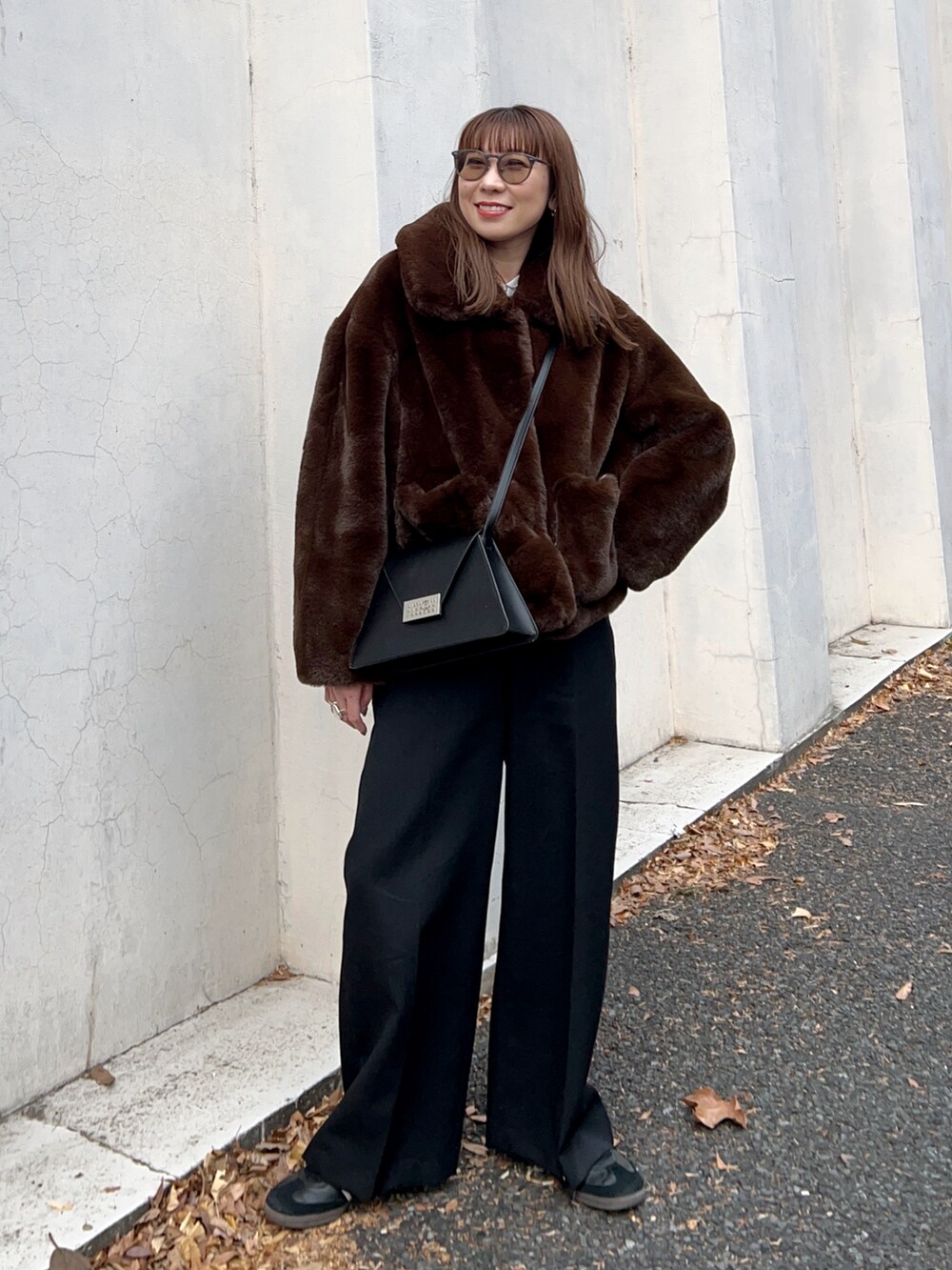 ブラウン系のブルゾン、ブラック系のショルダーバッグ、ホワイト系のTシャツ/カットソーを着用したレディースの冬コーディネートの2枚目の写真