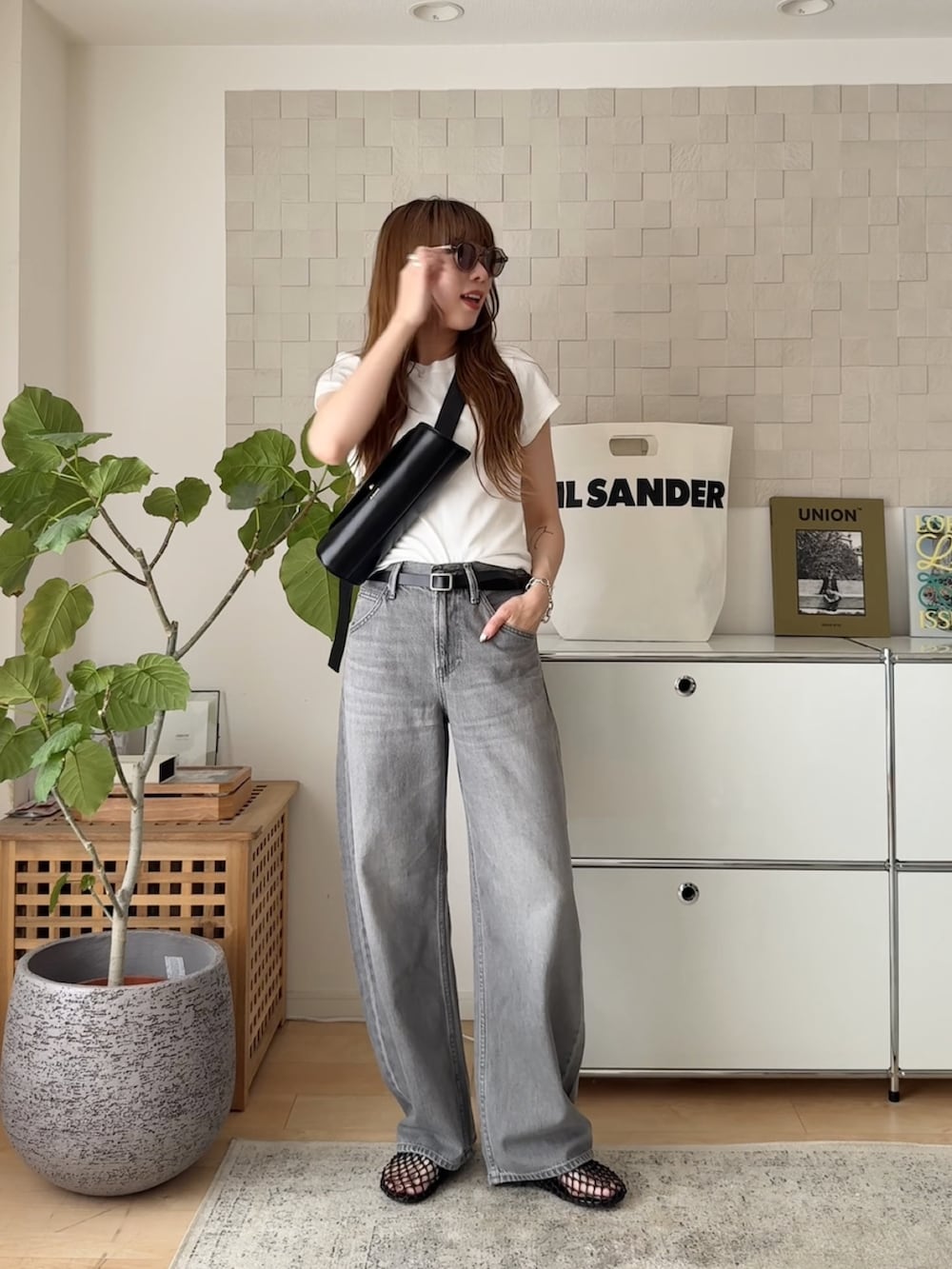 ブラック系のショルダーバッグ、ブラック系のサンダル、グレー系のデニムパンツを着用したレディースの夏コーディネートの2枚目の写真