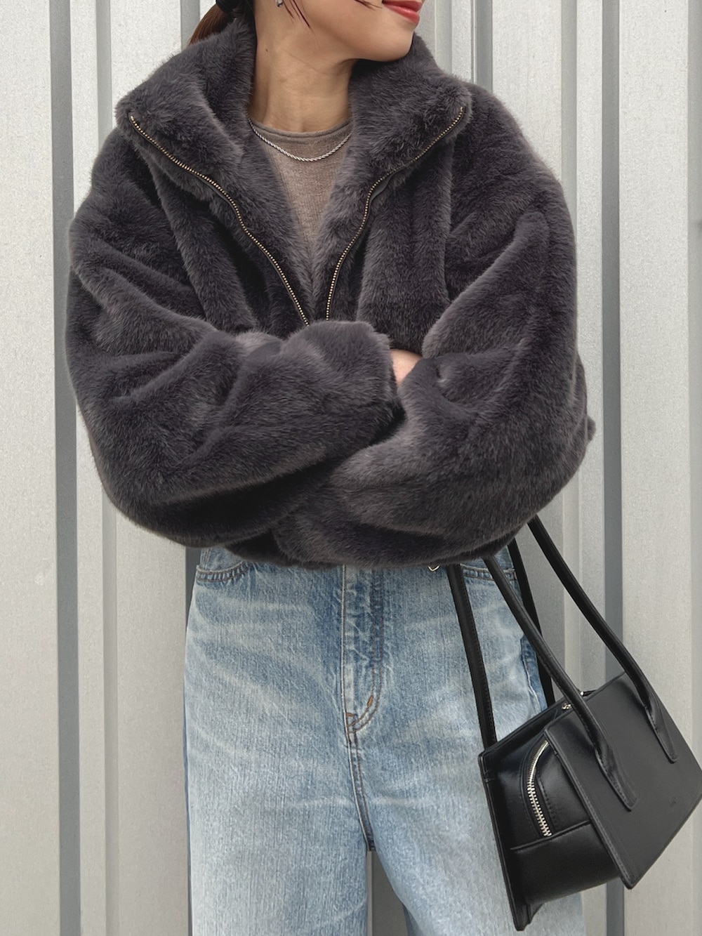 グレー系のブルゾン、ブルー系のデニムパンツ、ブラック系のブーツを着用したレディースの秋コーディネートの3枚目の写真