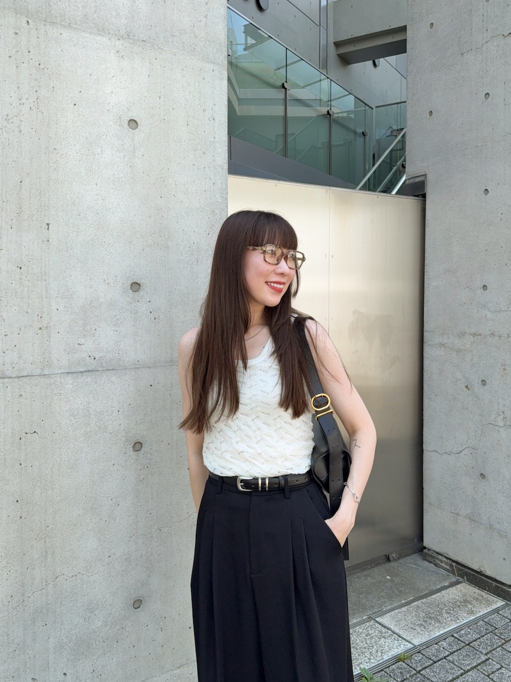 ホワイト系のタンクトップ、ブラック系のスラックス、ブラック系のサンダルを着用したレディースの夏コーディネートの4枚目の写真