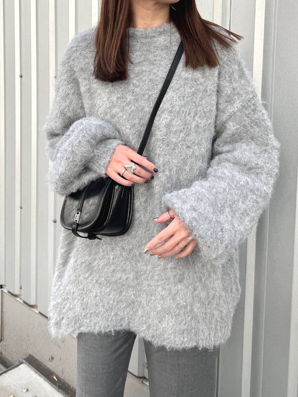 グレー系のニット/セーター、ブラック系のショルダーバッグ、グレー系のスラックスを着用したレディースの冬コーディネートの4枚目の写真