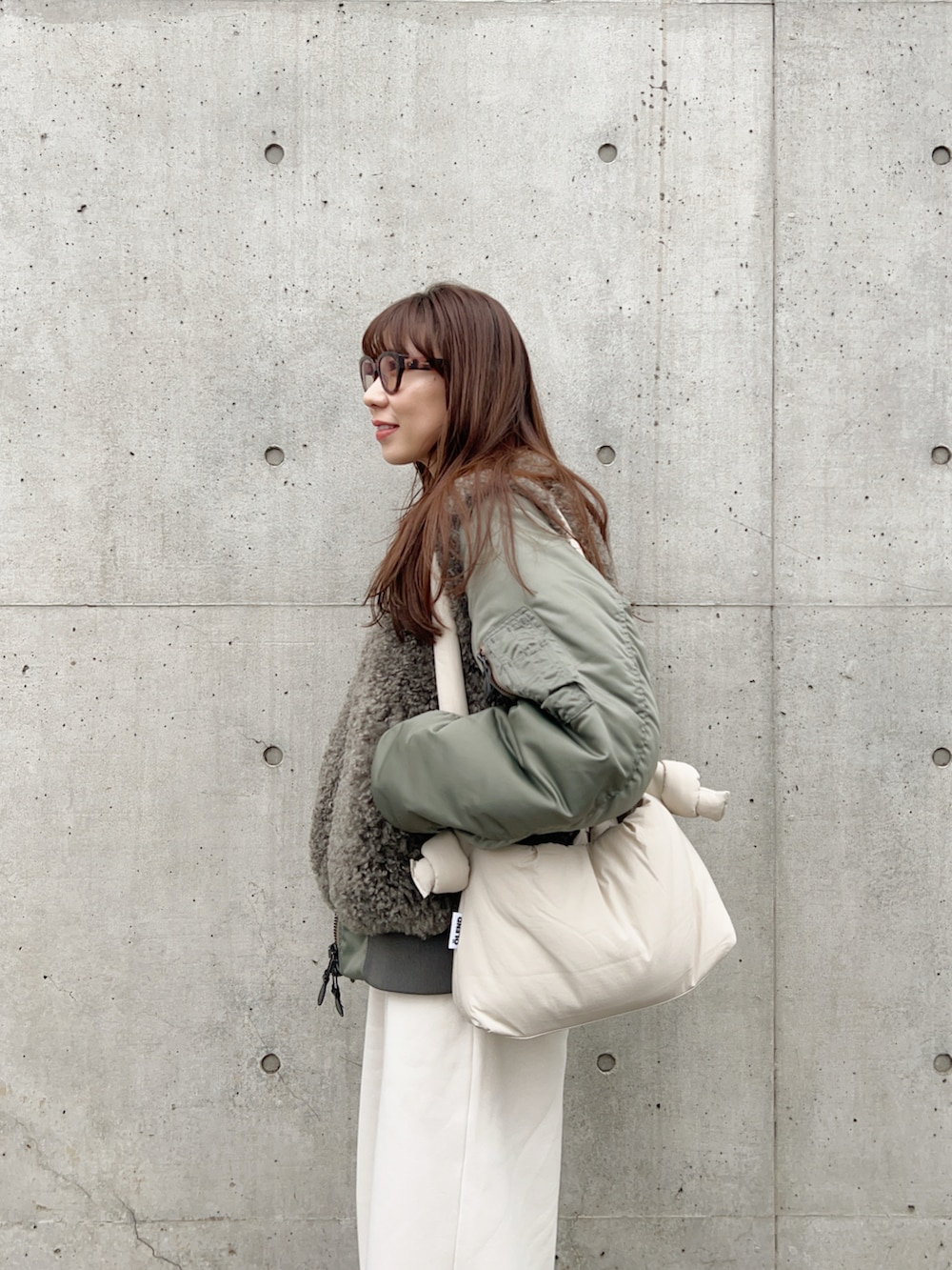 グリーン系のMA-1、ホワイト系のニット/セーター、ホワイト系のスウェットパンツを着用したレディースの冬コーディネートの3枚目の写真