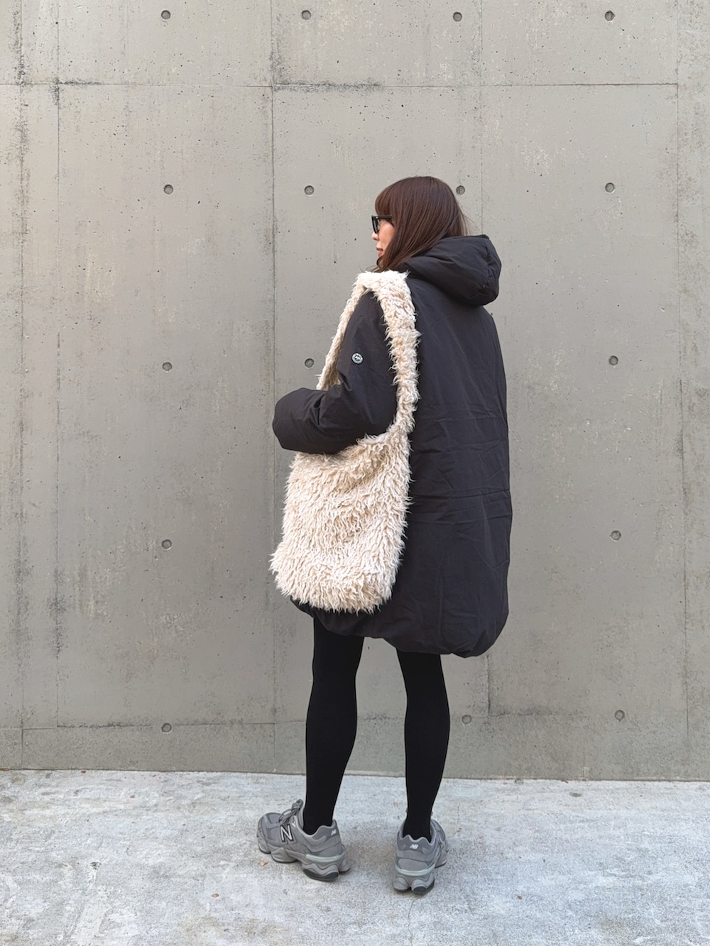 ブラック系のダウンジャケット/コート、ベージュ系のショルダーバッグ、グレー系のスニーカーを着用したレディースの冬コーディネートの3枚目の写真
