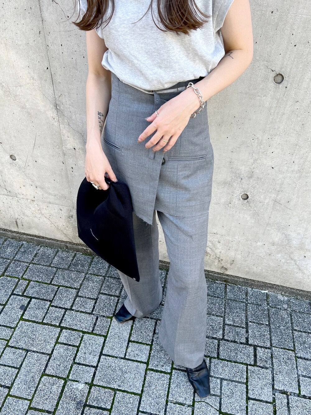 グレー系のTシャツ/カットソー、グレー系のスラックス、ブラック系のトートバッグを着用したレディースの秋コーディネートの4枚目の写真