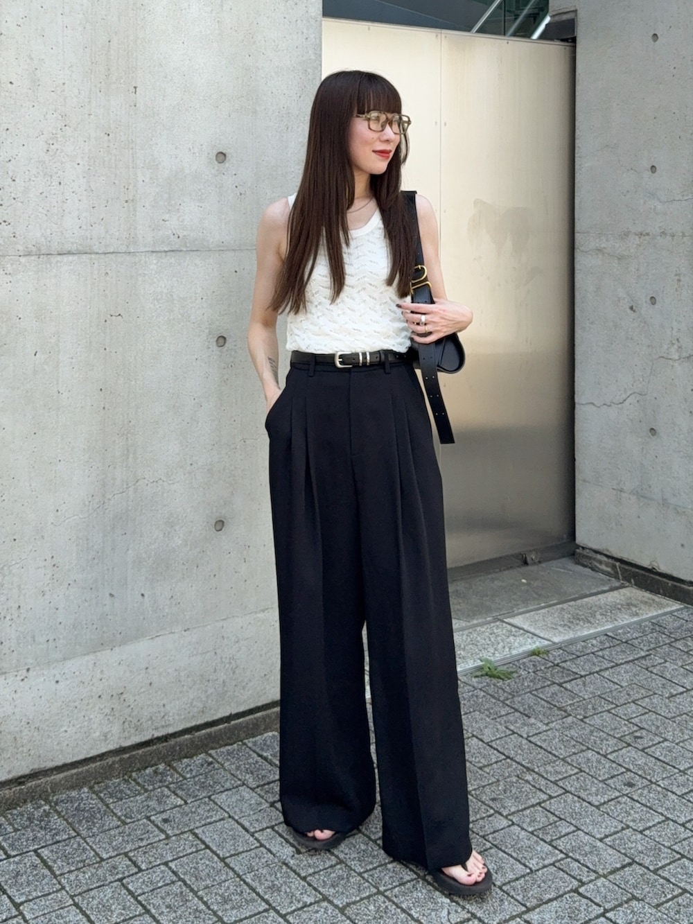 ホワイト系のタンクトップ、ブラック系のスラックス、ブラック系のサンダルを着用したレディースの夏コーディネートの2枚目の写真