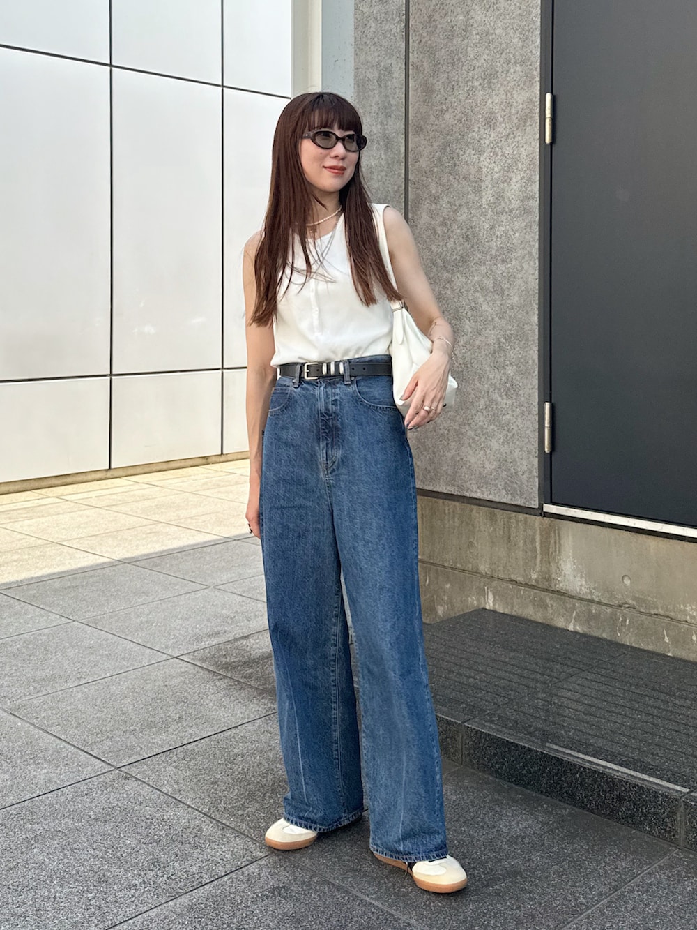 ホワイト系のタンクトップ、ブルー系のデニムパンツ、ホワイト系のスニーカーを着用したレディースの夏コーディネートの2枚目の写真