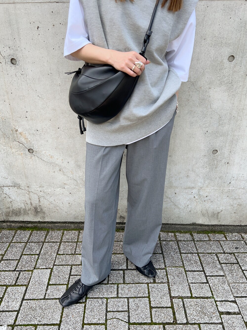 グレー系のニット/セーター、ブラック系のスリッポン、ホワイト系のTシャツ/カットソーを着用したレディースの春コーディネートの5枚目の写真