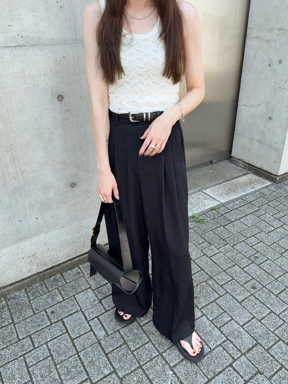 ホワイト系のタンクトップ、ブラック系のスラックス、ブラック系のサンダルを着用したレディースの夏コーディネートの5枚目の写真