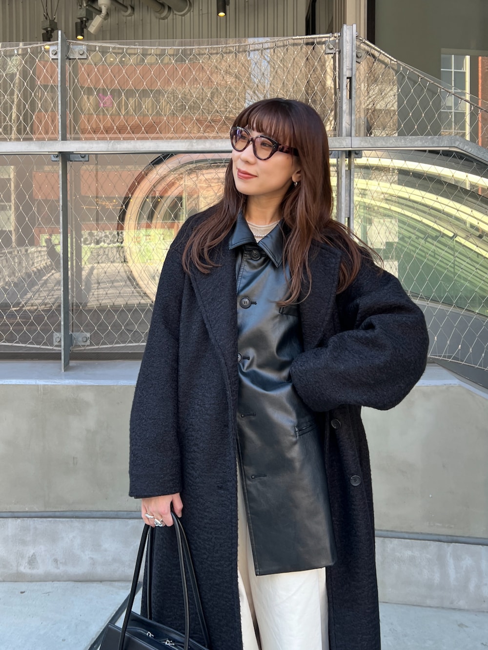 ブラック系のステンカラーコート、ブラック系のその他アウター、ホワイト系のニット/セーターを着用したレディースの冬コーディネートの4枚目の写真