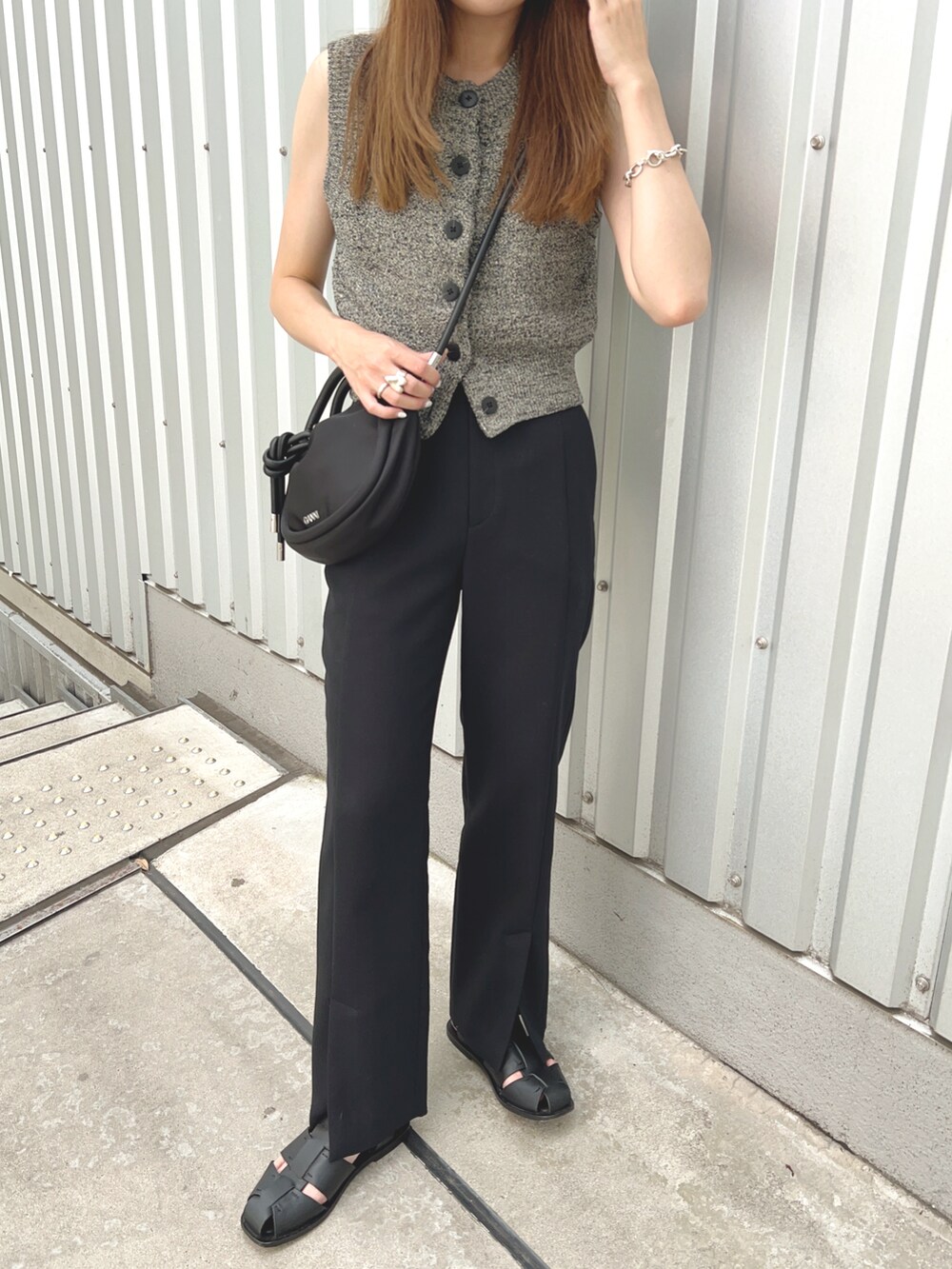ブラック系のベスト、ブラック系のショルダーバッグ、ブラック系のパンツを着用したレディースの夏コーディネートの3枚目の写真
