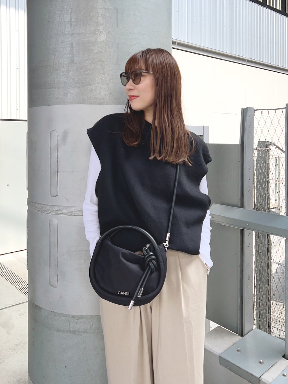 ブラック系のニット/セーター、ブラック系のハンドバッグ、ブラック系のスニーカーを着用したレディースの春コーディネートの3枚目の写真