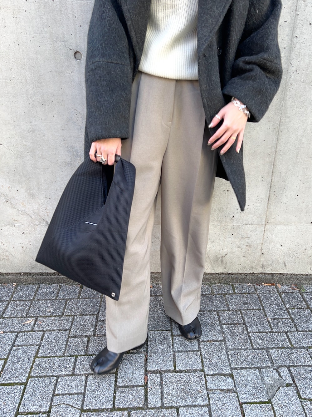 ブラック系のピーコート、ホワイト系のニット/セーター、ベージュ系のその他パンツを着用したレディースの冬コーディネートの5枚目の写真