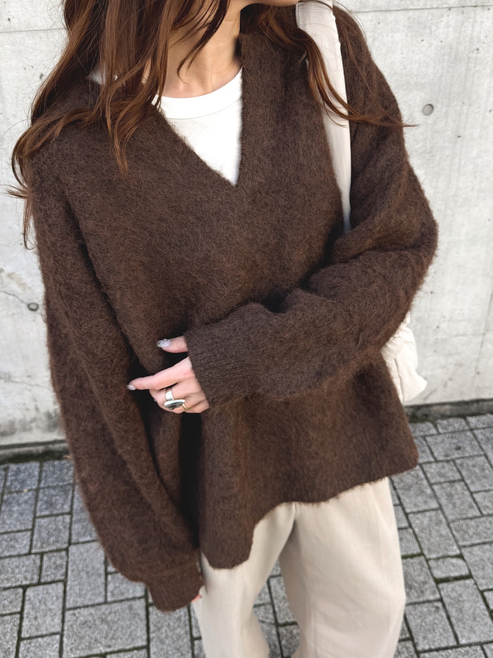 ブラウン系のニット/セーター、ベージュ系のパンツ、ベージュ系のハンドバッグを着用したレディースの秋コーディネートの3枚目の写真