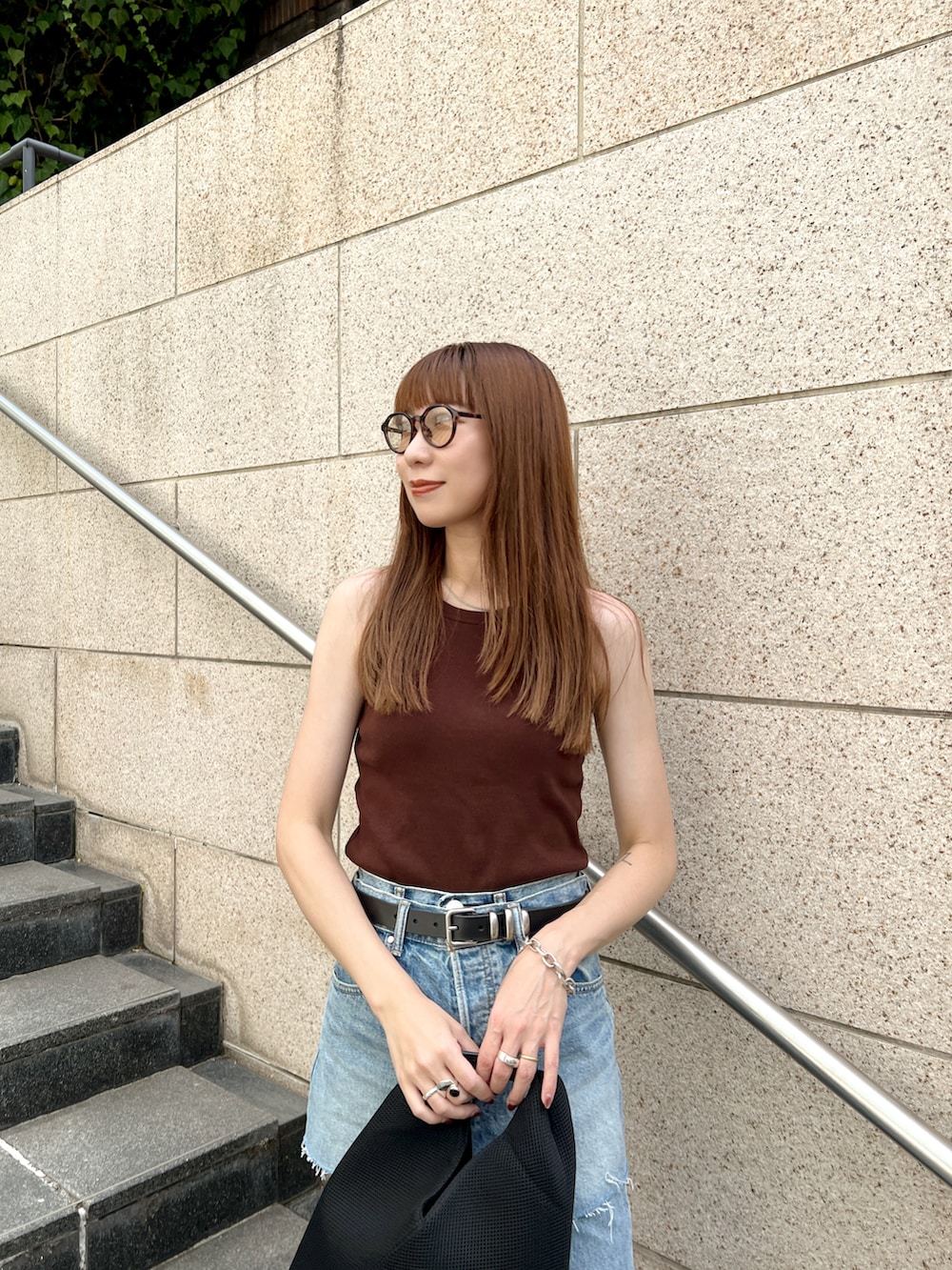 ブルー系のデニムパンツ、ブラック系のショルダーバッグ、ブラウン系のタンクトップを着用したレディースの夏コーディネートの3枚目の写真