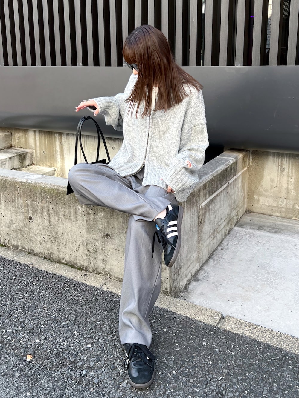 グレー系のニット/セーター、グレー系のスラックス、ブラック系のスニーカーを着用したレディースの秋コーディネートの4枚目の写真