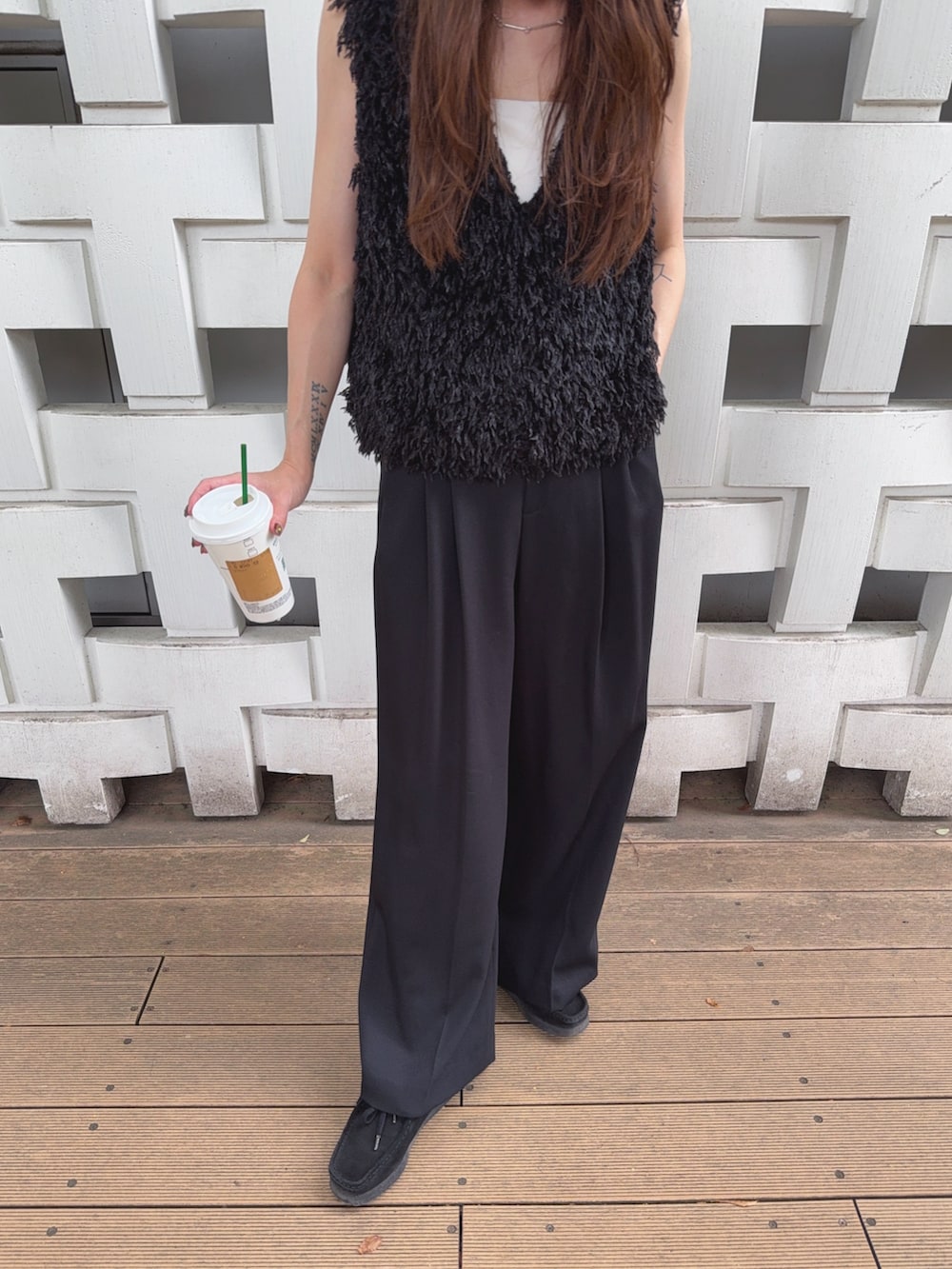 ブラック系のベスト、ブラック系のスラックス、ブラック系のバッグを着用したレディースの秋コーディネートの4枚目の写真