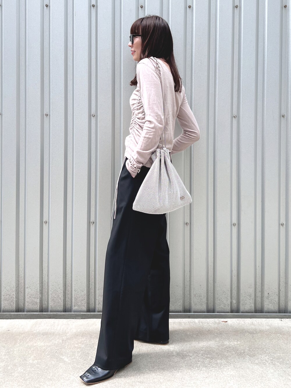 グレー系のニット/セーター、シルバー系のショルダーバッグ、ブラック系のパンツを着用したレディースの秋コーディネートの3枚目の写真