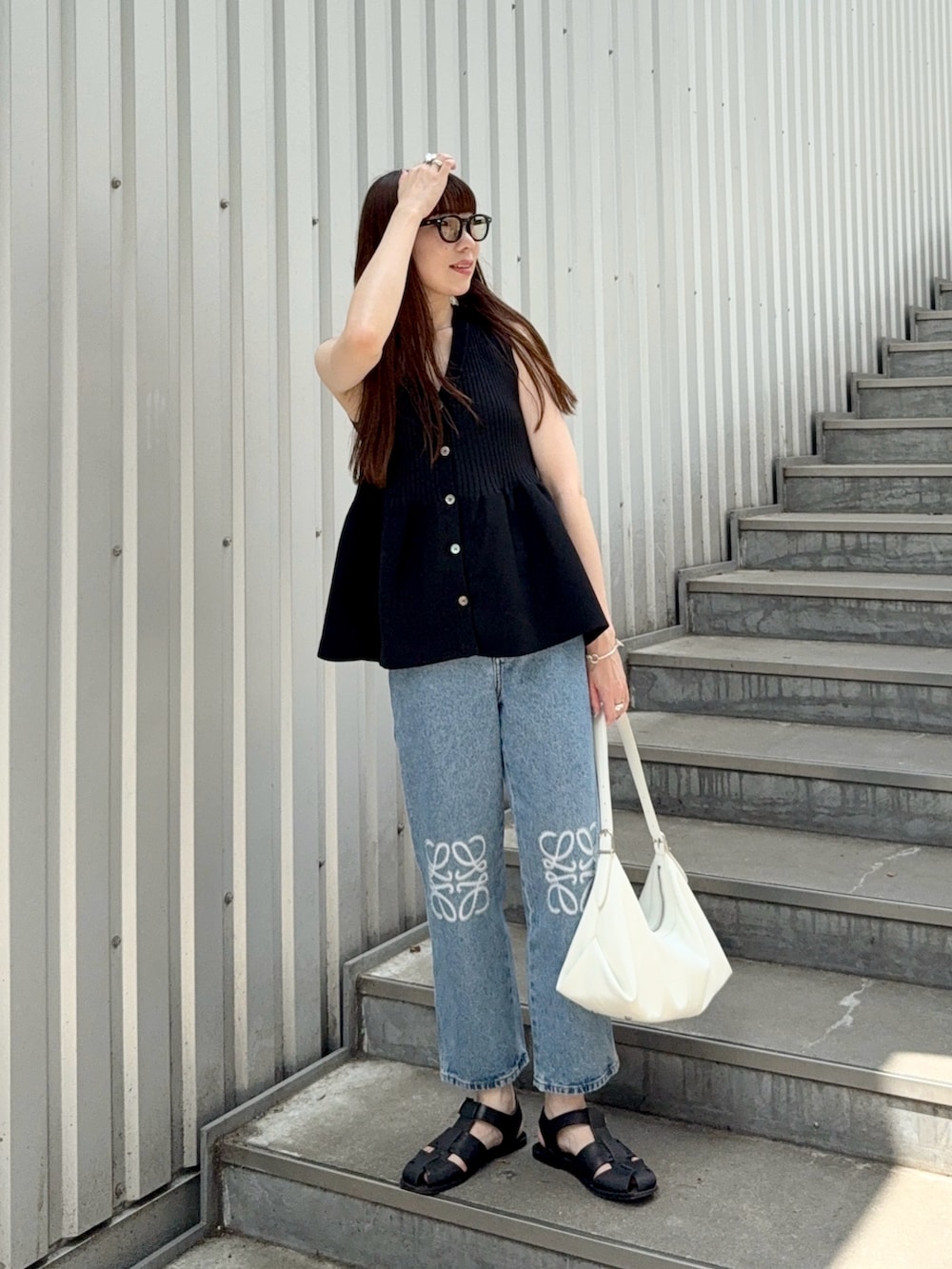 ブラック系のニット/セーター、ブラック系のサンダル、ブルー系のデニムパンツを着用したレディースの夏コーディネートの2枚目の写真