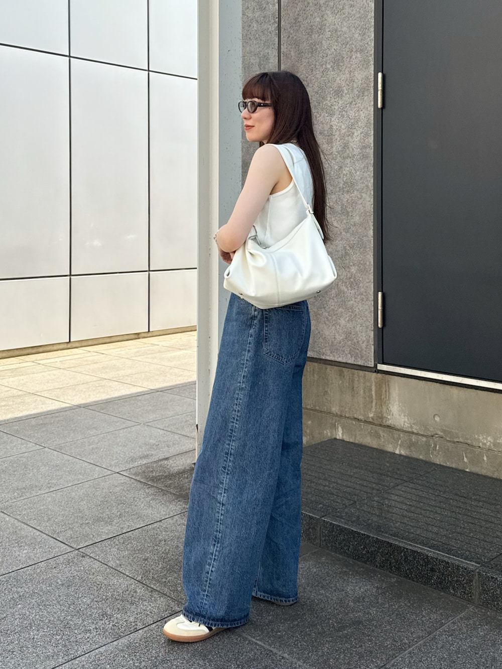 ホワイト系のタンクトップ、ブルー系のデニムパンツ、ホワイト系のスニーカーを着用したレディースの夏コーディネートの3枚目の写真