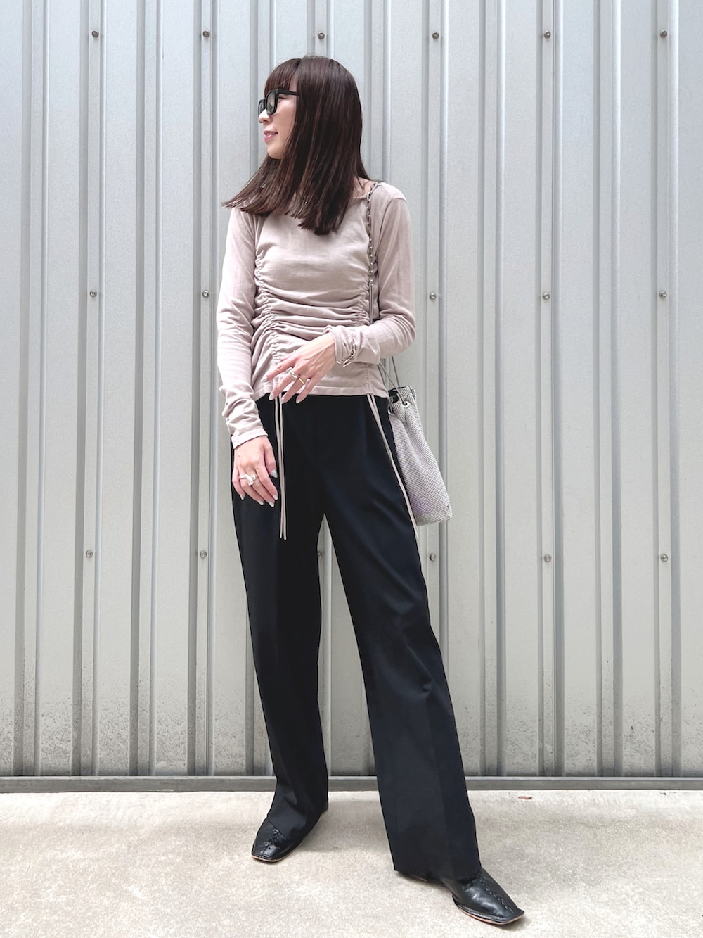 グレー系のニット/セーター、シルバー系のショルダーバッグ、ブラック系のパンツを着用したレディースの秋コーディネートの2枚目の写真