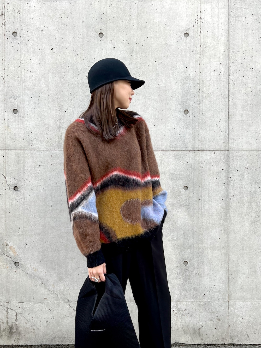 ブラック系のニット/セーター、ブラック系のトートバッグ、ブラック系のスラックスを着用したレディースの秋コーディネートの4枚目の写真